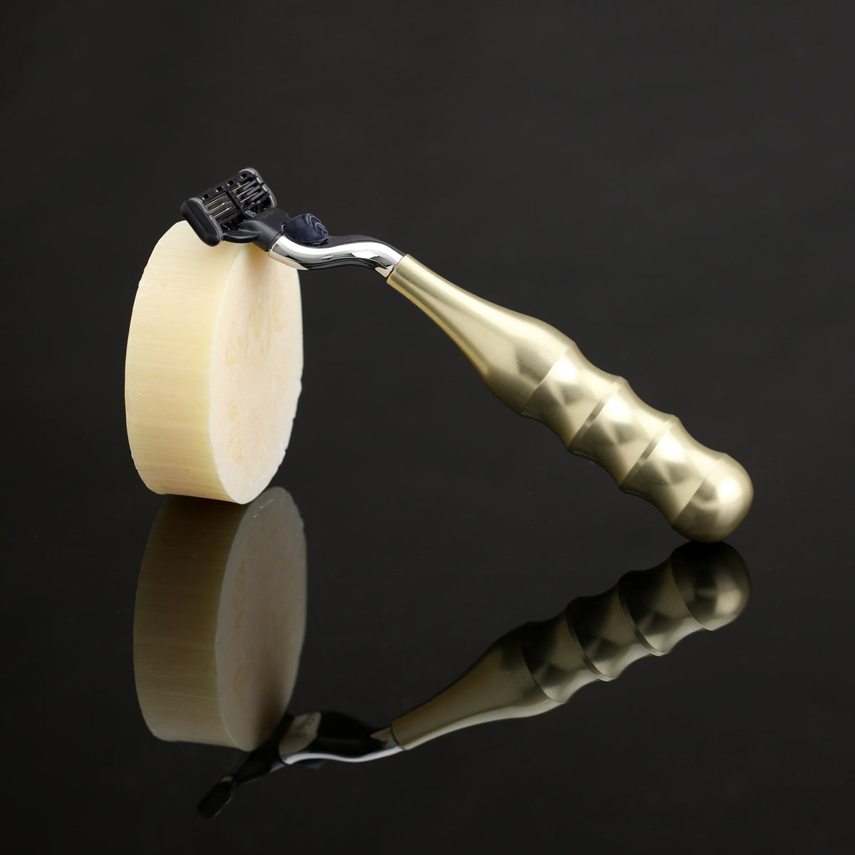 The Champagne-coloured mach3 Merker razor with a puck of shave soap on a black reflective background